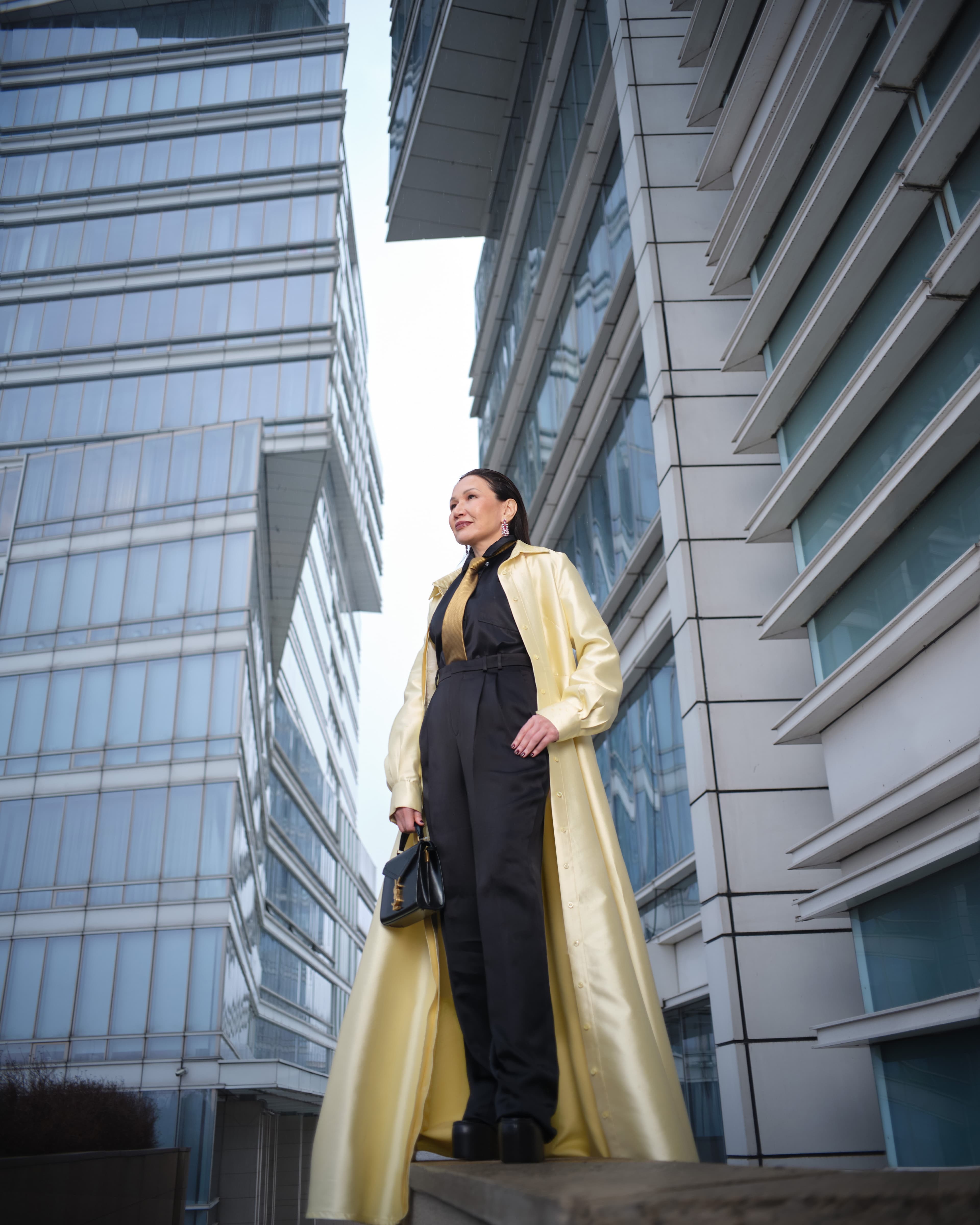 Атласное платье-рубашка, надетое как пальто Greta Constantine
Брюки и сумка Saint Laurent
Рубашка Loewe
Галстук Zegna
Туфли Gucci
Серьги Chopard High Jewellery